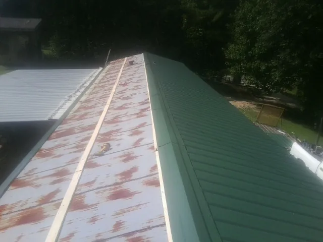 Old rusted panels beside newly installed green metal roofing — Wind Damage Roof Repair by Roofing Brothers in Sidney