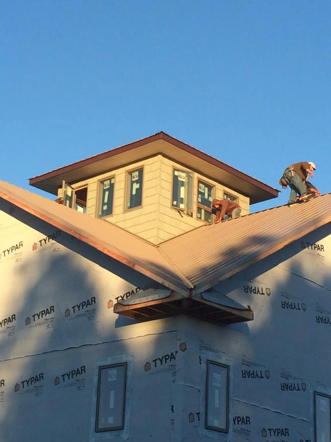 Roofers working around a rooftop cupola on a new metal roof at sunset — Roof Waterproofing in Sidney by Roofing Brothers